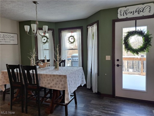 dining area with dark hardwood / wood-style floors, a textured ceiling, and a notable chandelier