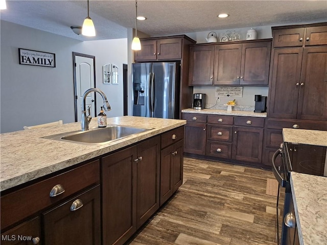 kitchen featuring stainless steel refrigerator with ice dispenser, dark brown cabinets, a textured ceiling, sink, and hanging light fixtures