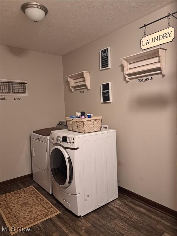 clothes washing area with washer and clothes dryer, dark hardwood / wood-style flooring, and a textured ceiling