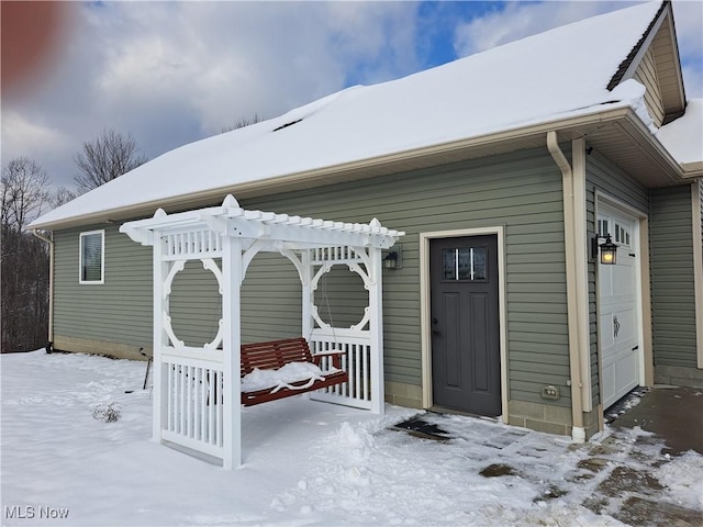 snow covered property entrance featuring a garage