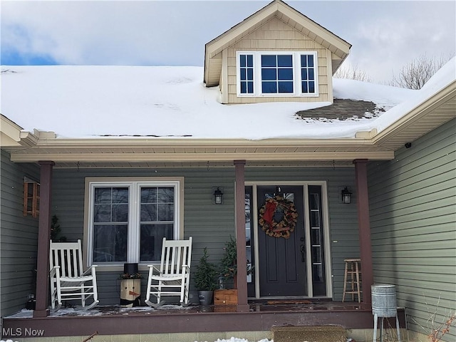 snow covered property entrance featuring a porch