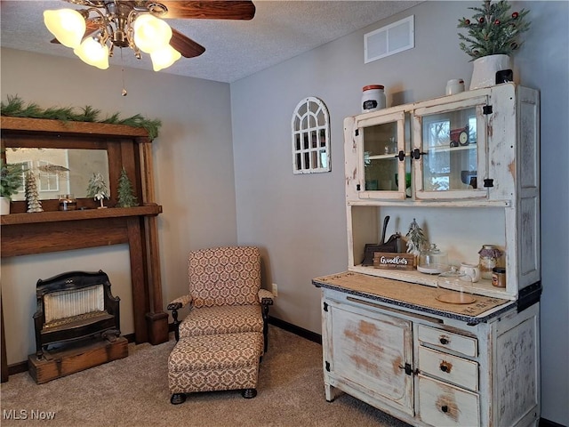 sitting room featuring ceiling fan, carpet floors, and a textured ceiling