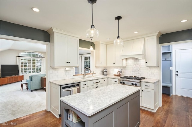 kitchen with custom range hood, white cabinetry, hanging light fixtures, and a kitchen island