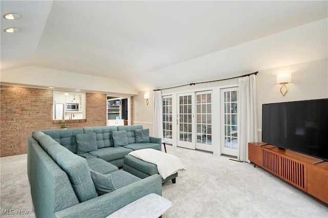 living room with brick wall, light colored carpet, and lofted ceiling