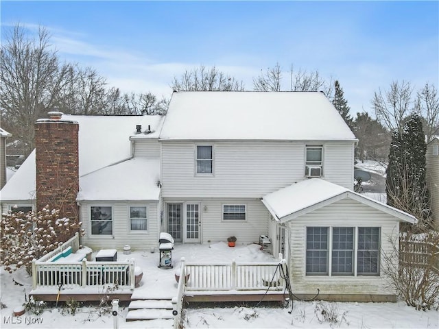 snow covered back of property with a deck and cooling unit