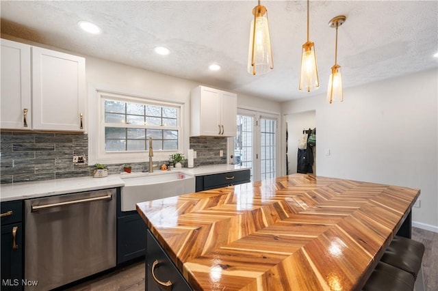 kitchen with white cabinetry, sink, hanging light fixtures, stainless steel dishwasher, and a kitchen island