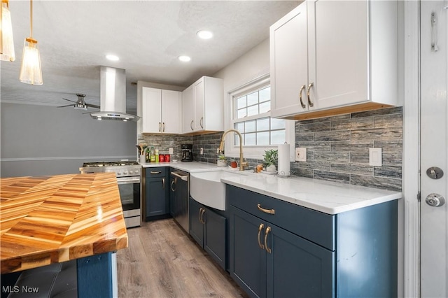 kitchen with appliances with stainless steel finishes, wall chimney exhaust hood, sink, light hardwood / wood-style flooring, and white cabinetry