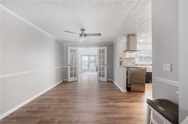 unfurnished living room featuring hardwood / wood-style floors, french doors, ceiling fan, ornamental molding, and a textured ceiling