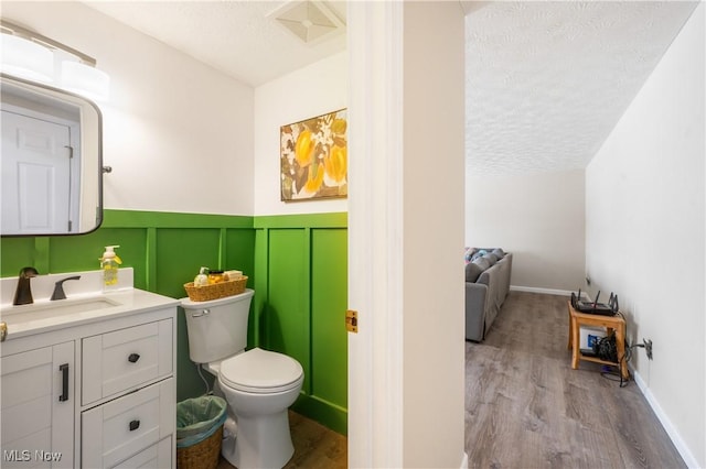 bathroom featuring vanity, wood-type flooring, a textured ceiling, and toilet