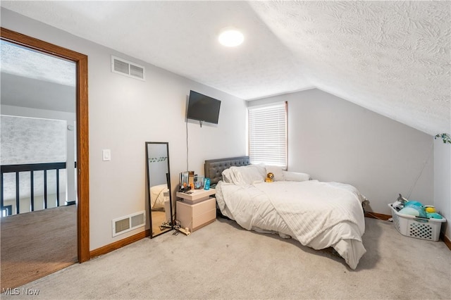 carpeted bedroom featuring vaulted ceiling and a textured ceiling