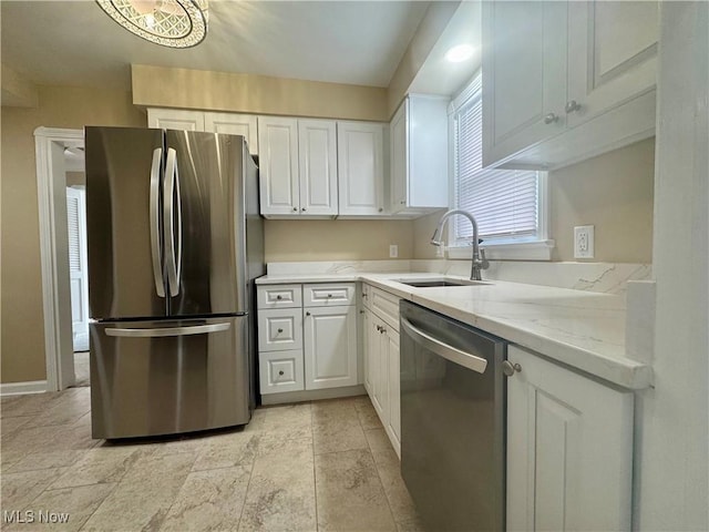 kitchen featuring white cabinetry, sink, light stone counters, and appliances with stainless steel finishes