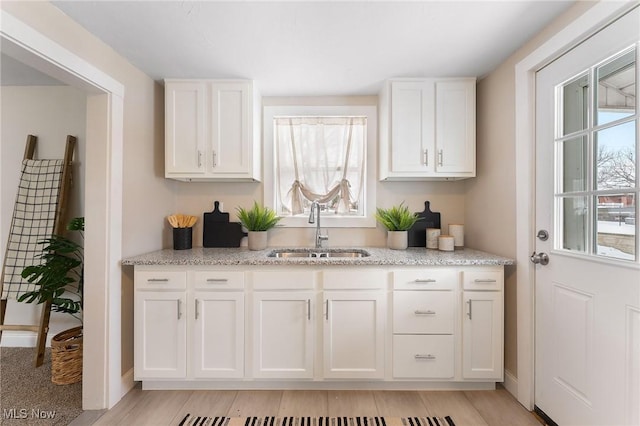 kitchen featuring white cabinetry, sink, and light stone countertops