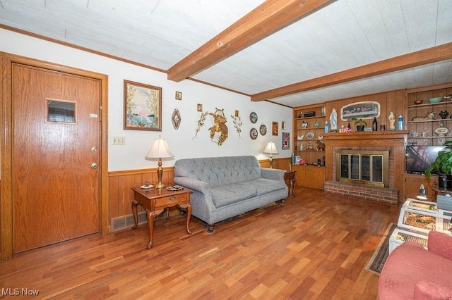 living room featuring built in shelves, wood walls, a fireplace, and hardwood / wood-style floors