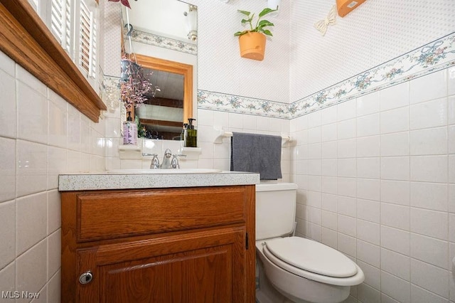 bathroom with vanity, toilet, and tile walls