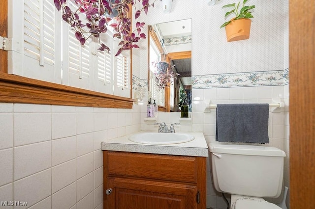 bathroom featuring vanity, toilet, and tile walls