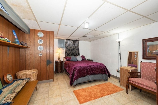 bedroom with a paneled ceiling and wood walls