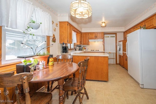 kitchen featuring kitchen peninsula, a chandelier, a healthy amount of sunlight, and white appliances