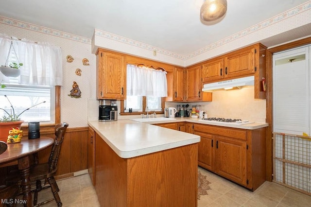 kitchen with kitchen peninsula, white gas cooktop, sink, and plenty of natural light