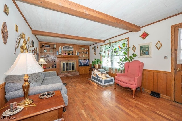 living room with wood walls, built in features, a fireplace, beam ceiling, and wood-type flooring