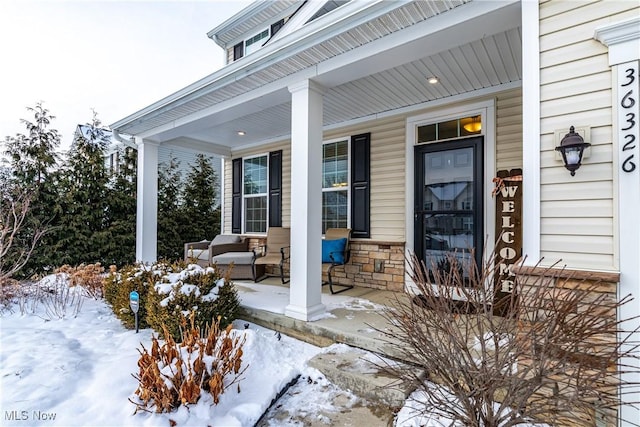 snow covered property entrance featuring a porch