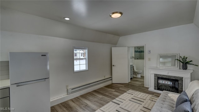 unfurnished living room with a fireplace, light hardwood / wood-style floors, vaulted ceiling, and baseboard heating