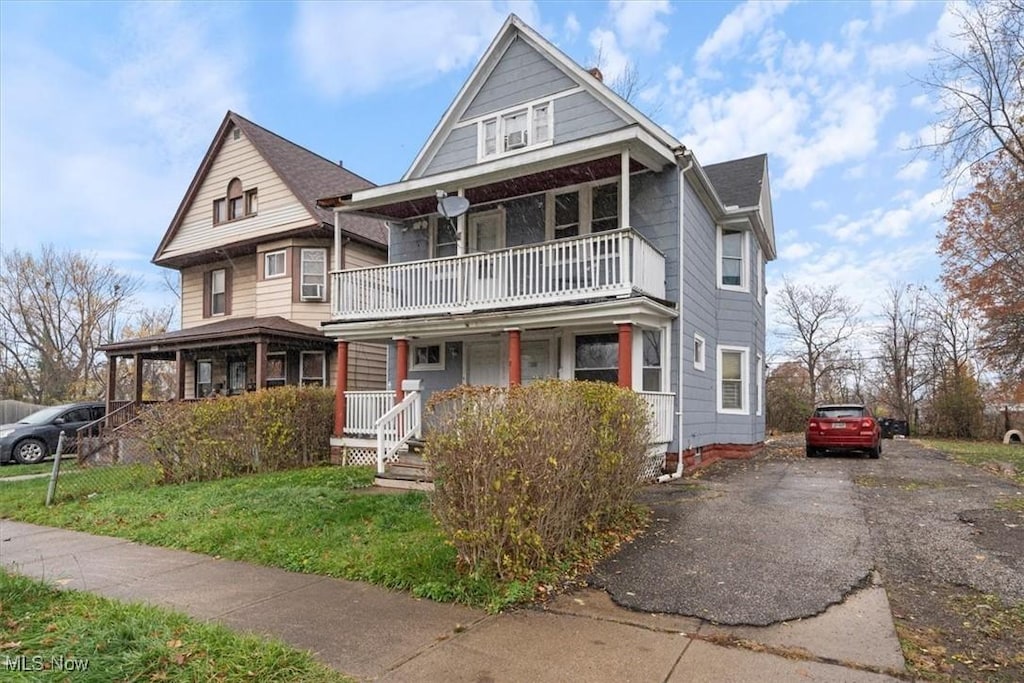 view of front facade with covered porch, a balcony, and a front lawn