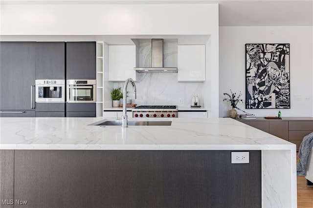 kitchen featuring light stone counters, sink, wall chimney exhaust hood, and hardwood / wood-style flooring