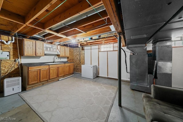 basement featuring heating unit, sink, and refrigerator