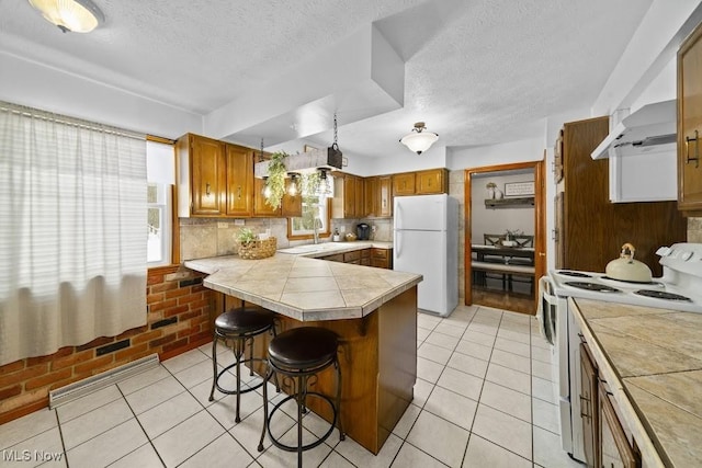 kitchen featuring a breakfast bar, light tile patterned floors, white appliances, and plenty of natural light