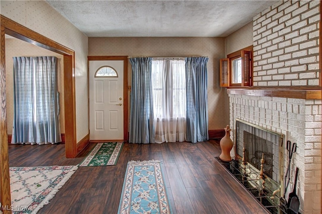 entrance foyer with a fireplace, a textured ceiling, and dark hardwood / wood-style floors