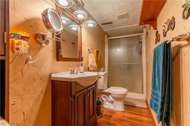 bathroom with a shower with shower door, vanity, wood-type flooring, and a textured ceiling