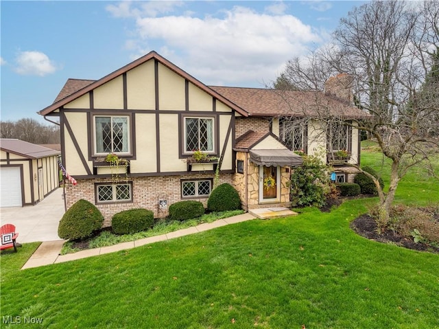 english style home with a garage, an outdoor structure, and a front yard