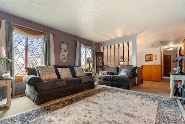 living room with a textured ceiling, light colored carpet, and wood walls