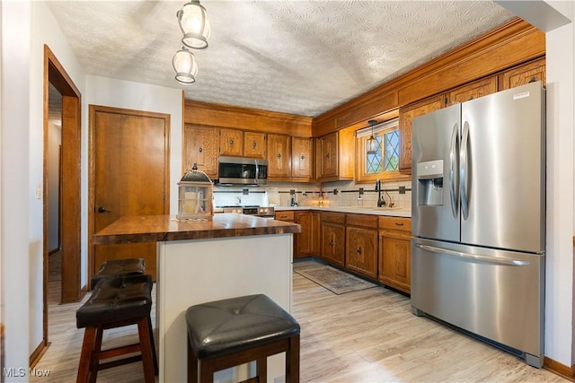 kitchen with a textured ceiling, decorative backsplash, sink, and stainless steel appliances