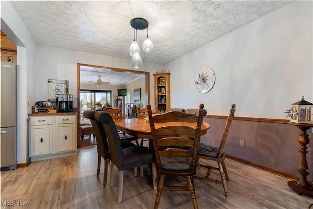 dining room with ceiling fan, light wood-type flooring, and a textured ceiling