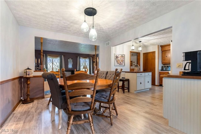 dining room with a textured ceiling and light hardwood / wood-style flooring