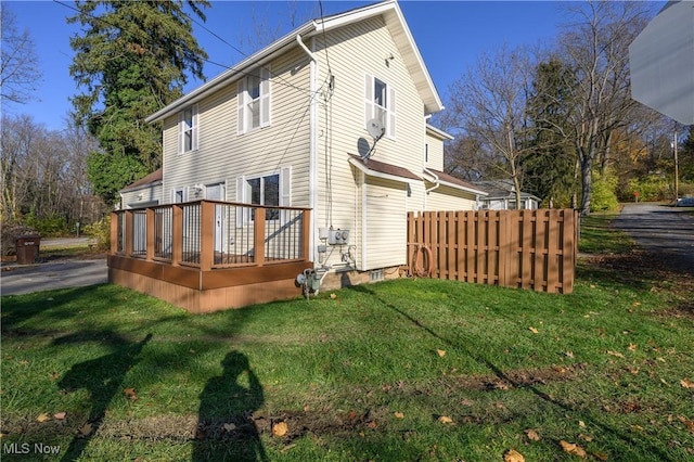 back of property featuring a lawn and a wooden deck