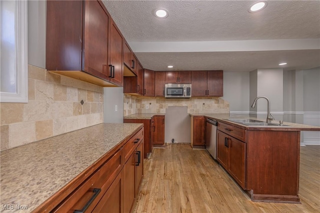 kitchen featuring sink, stainless steel appliances, light hardwood / wood-style floors, decorative backsplash, and a kitchen island