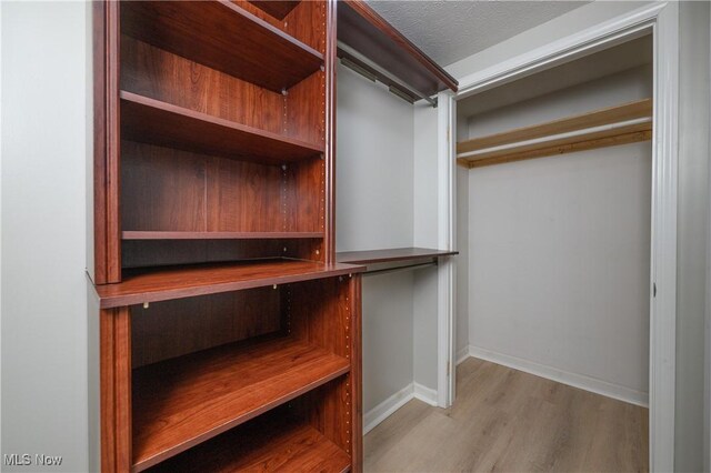 walk in closet with light hardwood / wood-style floors