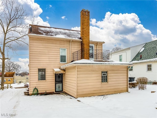 snow covered rear of property with a balcony