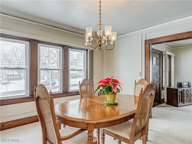 carpeted dining room with ornamental molding and an inviting chandelier