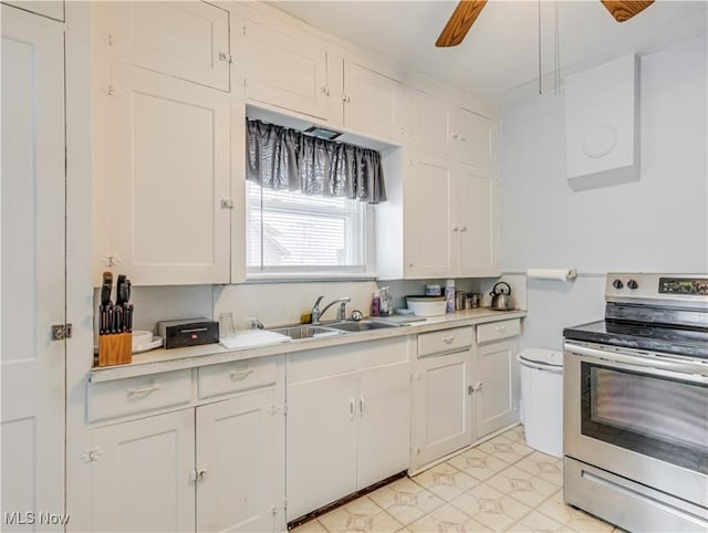 kitchen with white cabinets, light tile patterned flooring, stainless steel range with electric stovetop, and sink