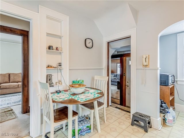 dining room with built in shelves and vaulted ceiling