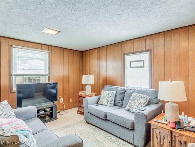 carpeted living room featuring wood walls and a textured ceiling