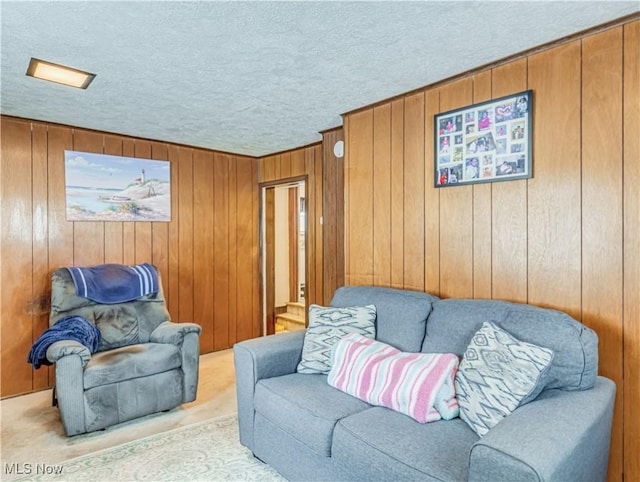 living room featuring a textured ceiling, light colored carpet, and wooden walls