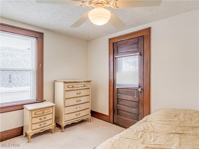 carpeted bedroom with ceiling fan and a textured ceiling