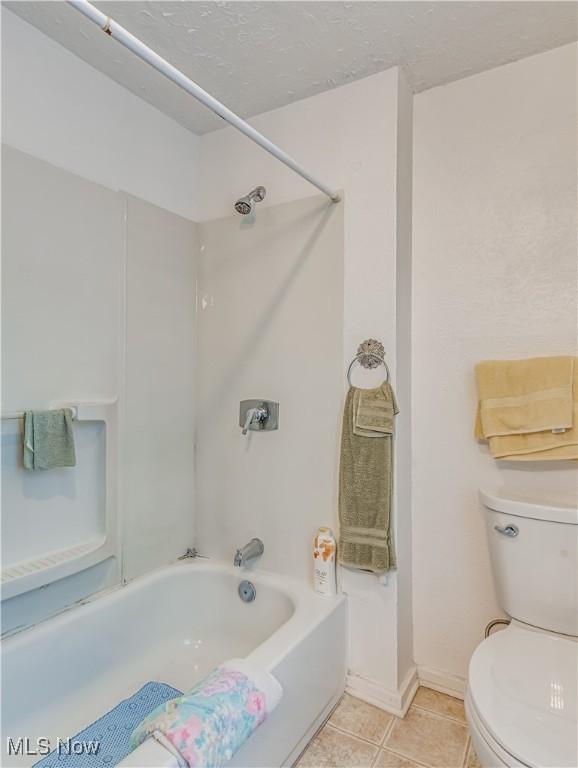 bathroom with tile patterned flooring, a textured ceiling,  shower combination, and toilet