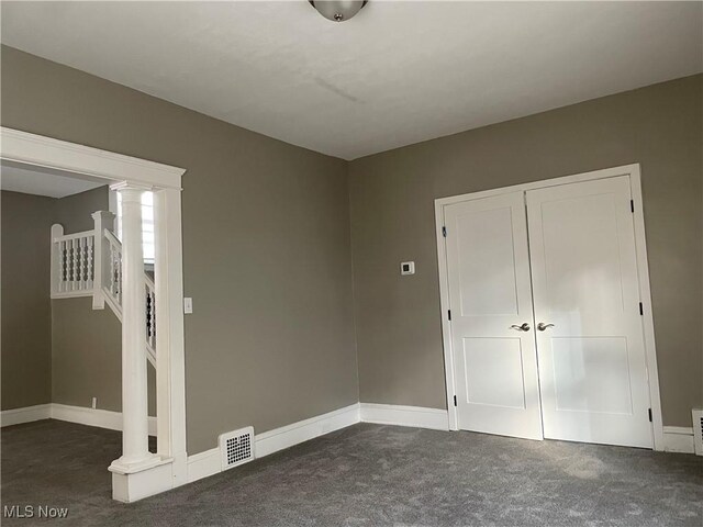 unfurnished bedroom with dark colored carpet and a closet