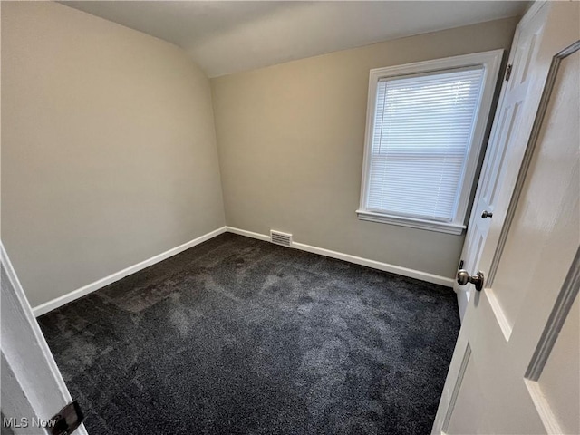 spare room with carpet floors and vaulted ceiling