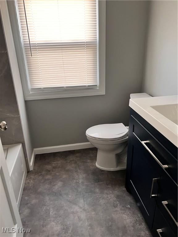 bathroom with a bathing tub, vanity, and toilet